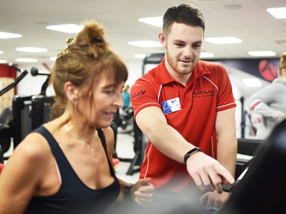 Lady on a treadmill with an Actif instructor alongside her showing how to use the machine