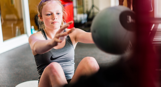 young girl in gym using weighted ball